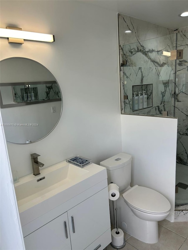 bathroom with tile patterned floors, vanity, toilet, and tiled shower