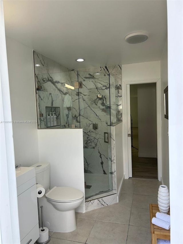 bathroom featuring tile patterned floors, vanity, toilet, and a shower with door