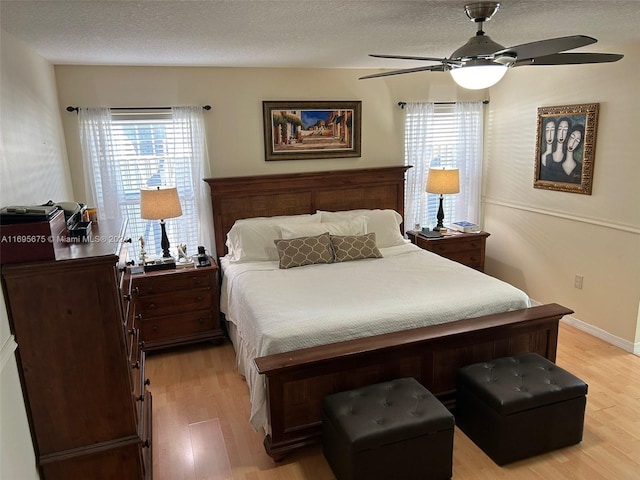 bedroom with ceiling fan, light hardwood / wood-style floors, and a textured ceiling