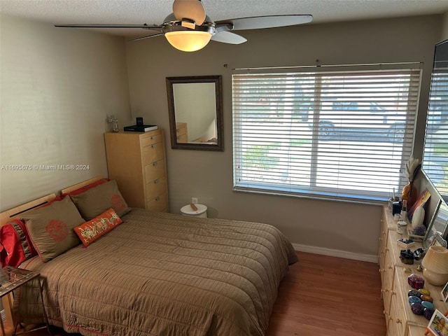 bedroom with hardwood / wood-style floors, ceiling fan, a textured ceiling, and multiple windows