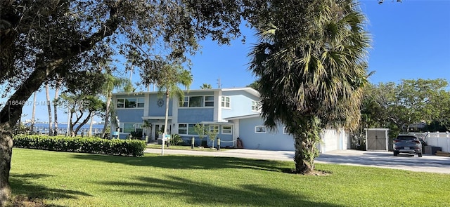 view of front facade featuring stucco siding, concrete driveway, a front yard, and fence