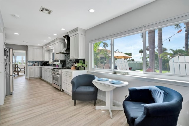 kitchen featuring visible vents, plenty of natural light, tasteful backsplash, stainless steel appliances, and wall chimney exhaust hood