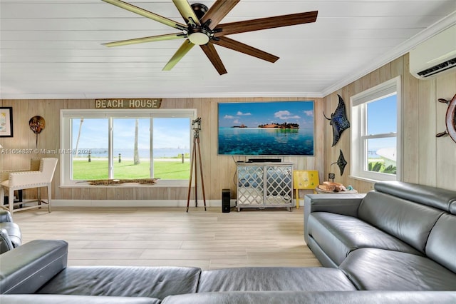 living room with an AC wall unit, light wood-style floors, crown molding, baseboards, and ceiling fan