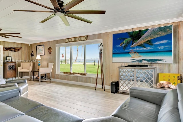 living area featuring baseboards, wood finished floors, a ceiling fan, and wood walls