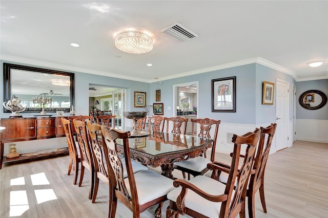 dining room with visible vents, ornamental molding, light wood-style floors, wainscoting, and a chandelier