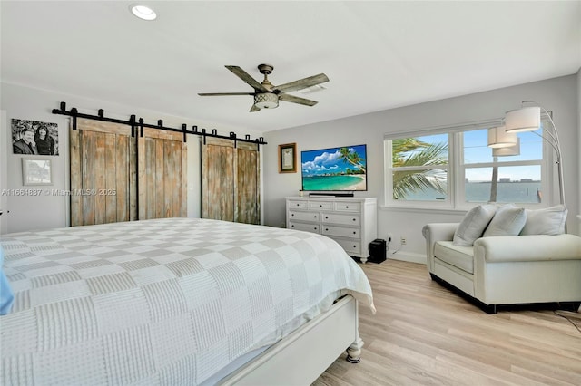 bedroom with light wood-type flooring, recessed lighting, a barn door, baseboards, and ceiling fan