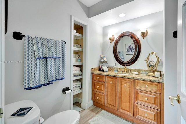 bathroom featuring toilet, wood finished floors, and vanity