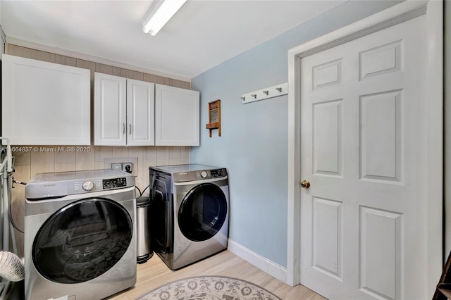 washroom featuring washer and dryer, light wood-style flooring, cabinet space, and baseboards