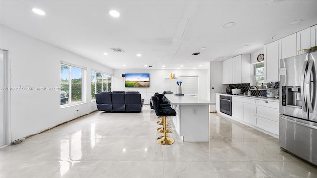 kitchen featuring sink, appliances with stainless steel finishes, a kitchen island, white cabinetry, and a breakfast bar area