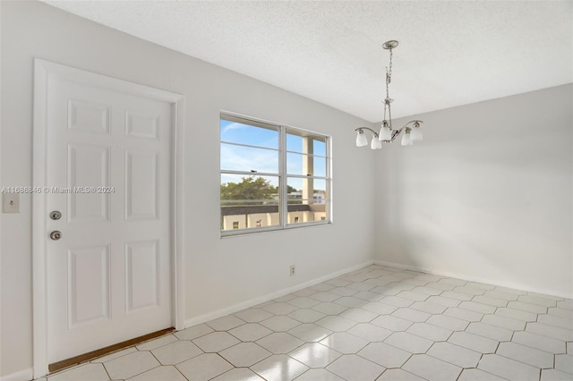 empty room featuring a chandelier and a textured ceiling