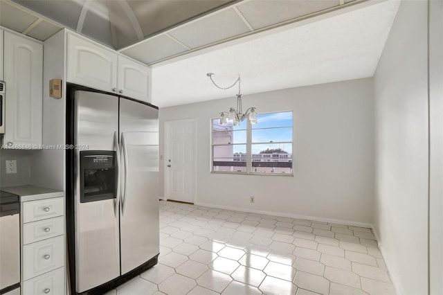 kitchen with white cabinets, a notable chandelier, stainless steel fridge, and hanging light fixtures