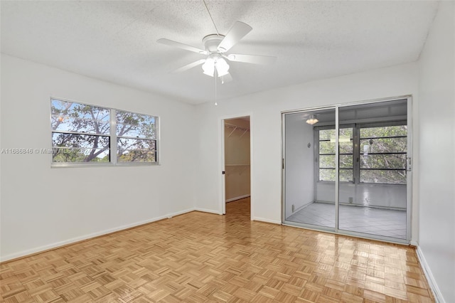 spare room featuring ceiling fan, light parquet floors, and a textured ceiling