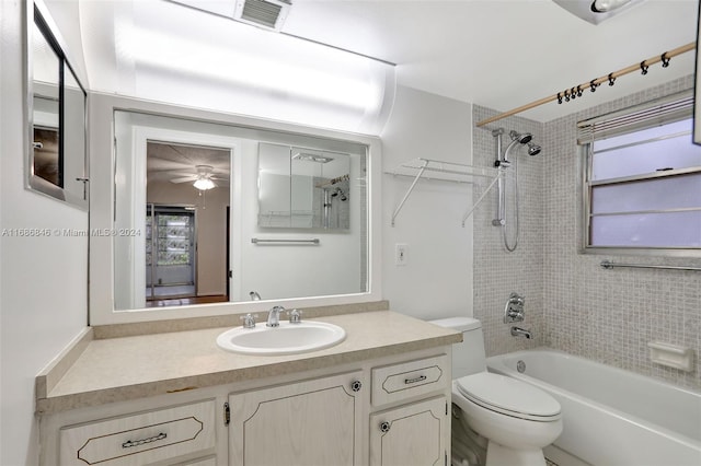 full bathroom featuring vanity, toilet, tiled shower / bath, and ceiling fan