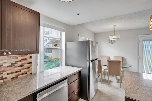 kitchen featuring light stone countertops, tasteful backsplash, pendant lighting, light tile patterned flooring, and appliances with stainless steel finishes