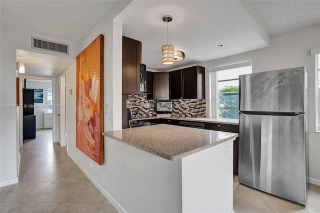 kitchen with hanging light fixtures, stainless steel fridge, a textured ceiling, tasteful backsplash, and light tile patterned flooring