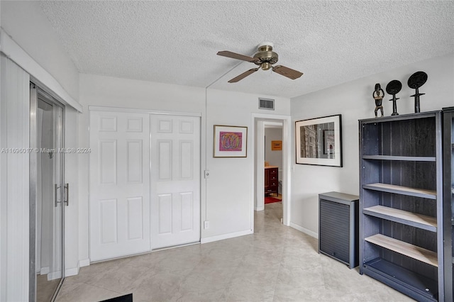 unfurnished bedroom featuring ceiling fan, a textured ceiling, and a closet