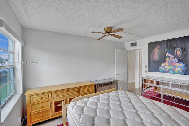 bedroom with ceiling fan and a textured ceiling