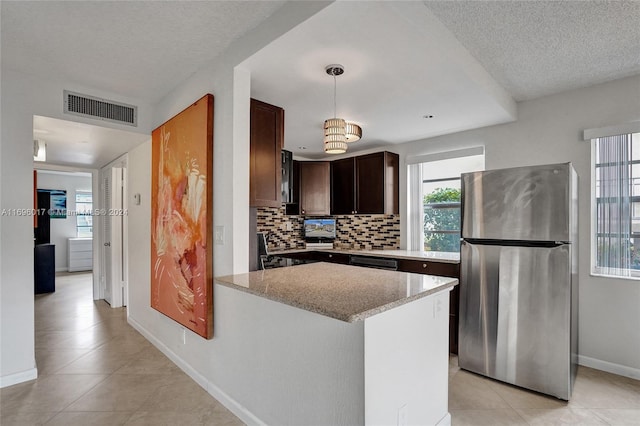 kitchen with backsplash, a textured ceiling, decorative light fixtures, light tile patterned flooring, and stainless steel refrigerator