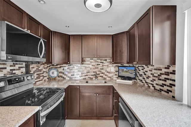 kitchen with dark brown cabinetry, decorative backsplash, sink, and appliances with stainless steel finishes