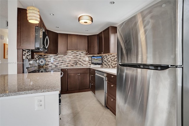 kitchen with backsplash, light stone counters, stainless steel appliances, sink, and pendant lighting