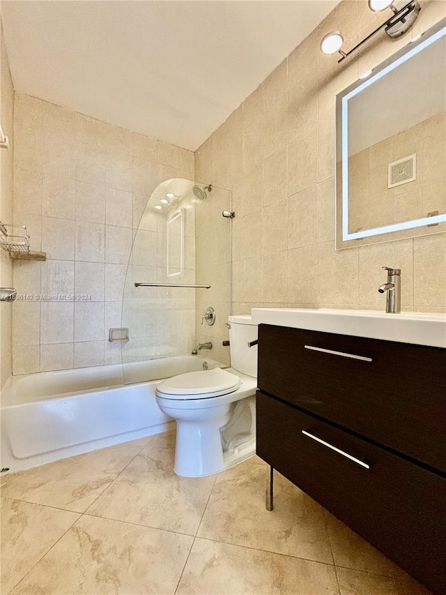 full bathroom featuring tile patterned flooring, toilet, vanity, tile walls, and tiled shower / bath