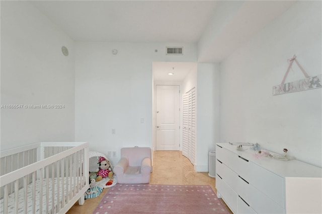 bedroom featuring a nursery area and light wood-type flooring