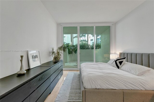 bedroom with access to outside, expansive windows, and light hardwood / wood-style floors