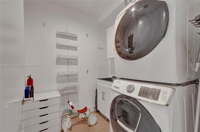 laundry area featuring cabinets and stacked washer and clothes dryer