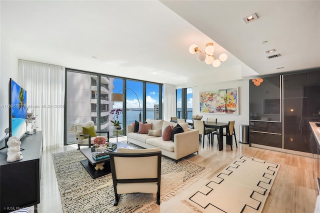 living room featuring floor to ceiling windows, light hardwood / wood-style flooring, and a water view