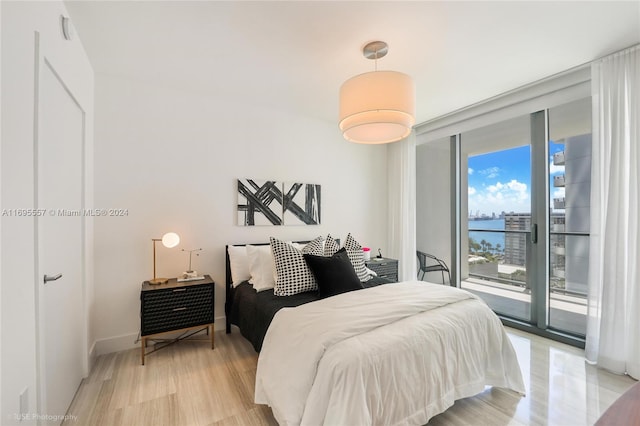 bedroom featuring access to exterior, expansive windows, and light wood-type flooring