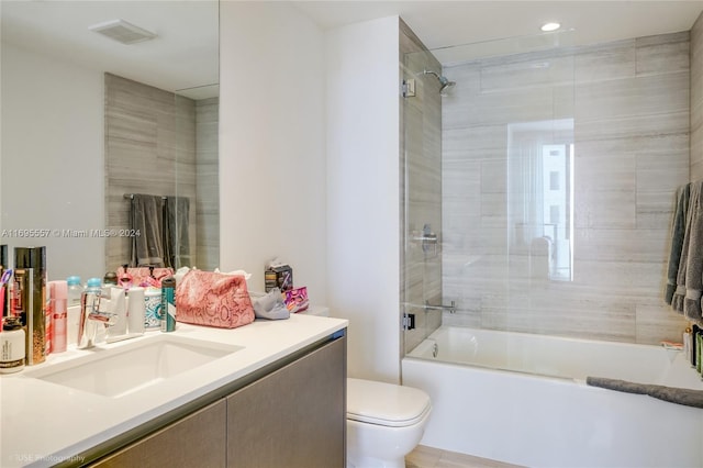 full bathroom featuring vanity, tiled shower / bath combo, and toilet