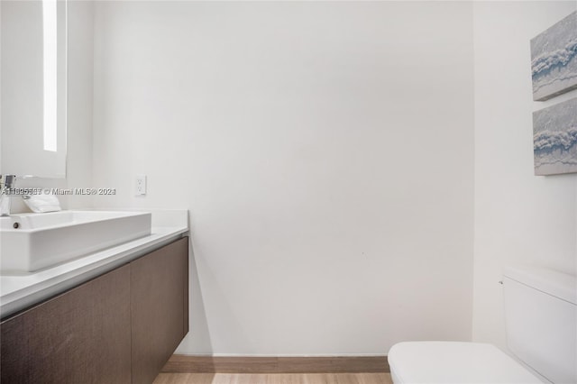 bathroom with hardwood / wood-style floors, vanity, and toilet