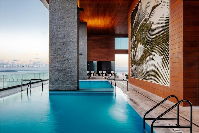 pool at dusk with a water view and a patio