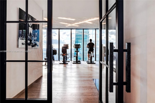 gym with hardwood / wood-style floors, french doors, and expansive windows