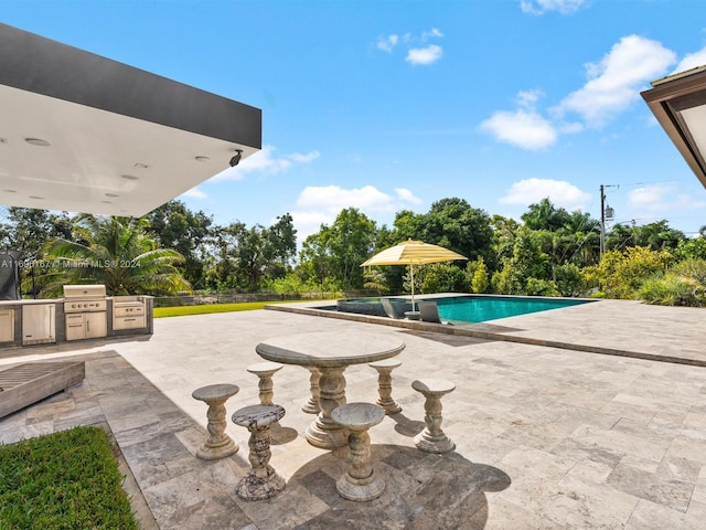 view of swimming pool featuring an outdoor kitchen, area for grilling, and a patio area