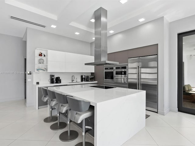 kitchen with island range hood, stainless steel built in fridge, a kitchen island, and light stone countertops