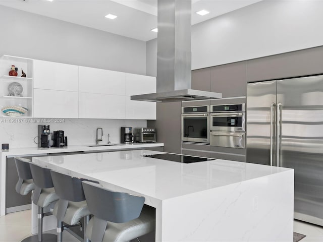 kitchen featuring island exhaust hood, stainless steel appliances, light stone counters, and a kitchen island