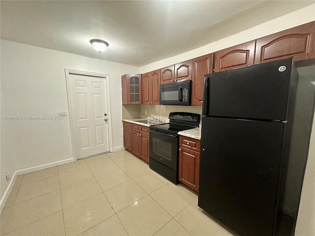 kitchen featuring sink, light tile patterned floors, black appliances, and a textured ceiling