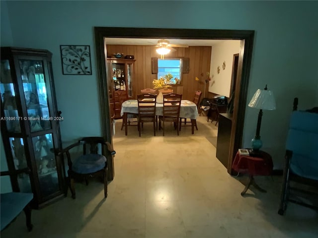 dining area featuring ceiling fan and wooden walls