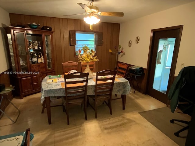 dining room with ceiling fan and wood walls