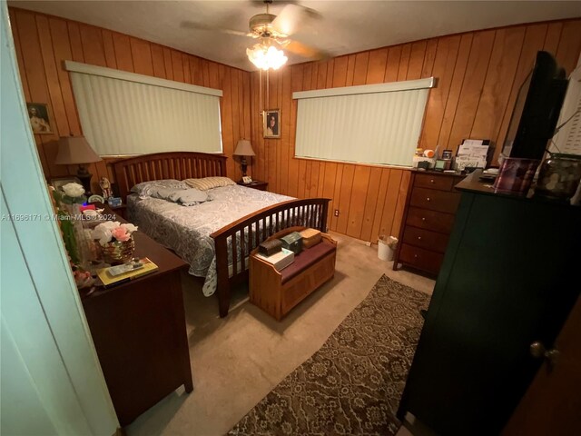 carpeted bedroom featuring ceiling fan and wooden walls