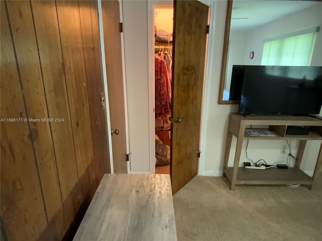 hallway featuring carpet flooring and wood walls