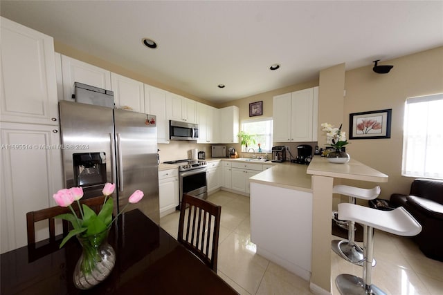 kitchen with kitchen peninsula, white cabinetry, sink, and appliances with stainless steel finishes