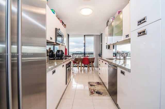 kitchen with light tile patterned flooring, appliances with stainless steel finishes, white cabinetry, and sink