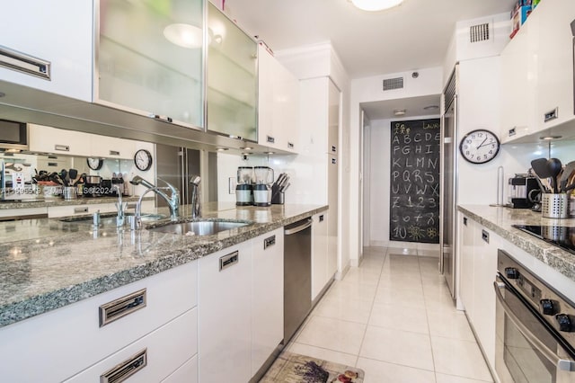 kitchen featuring stone counters, light tile patterned floors, white cabinetry, and appliances with stainless steel finishes