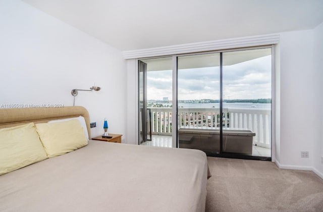 carpeted bedroom featuring access to outside, multiple windows, and a water view