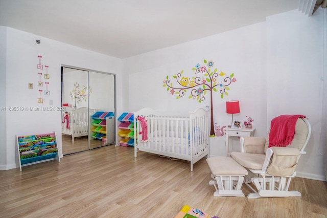 bedroom with a nursery area and wood-type flooring