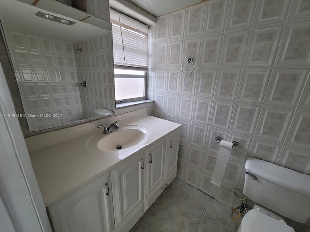 bathroom featuring tile patterned flooring, vanity, toilet, and tile walls