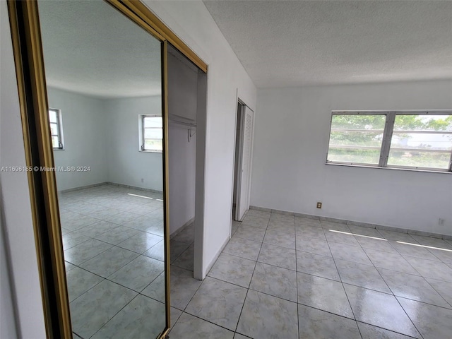 unfurnished bedroom with light tile patterned floors, a textured ceiling, and a closet