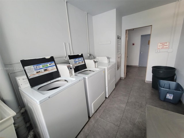 laundry room featuring washer and clothes dryer and dark tile patterned flooring